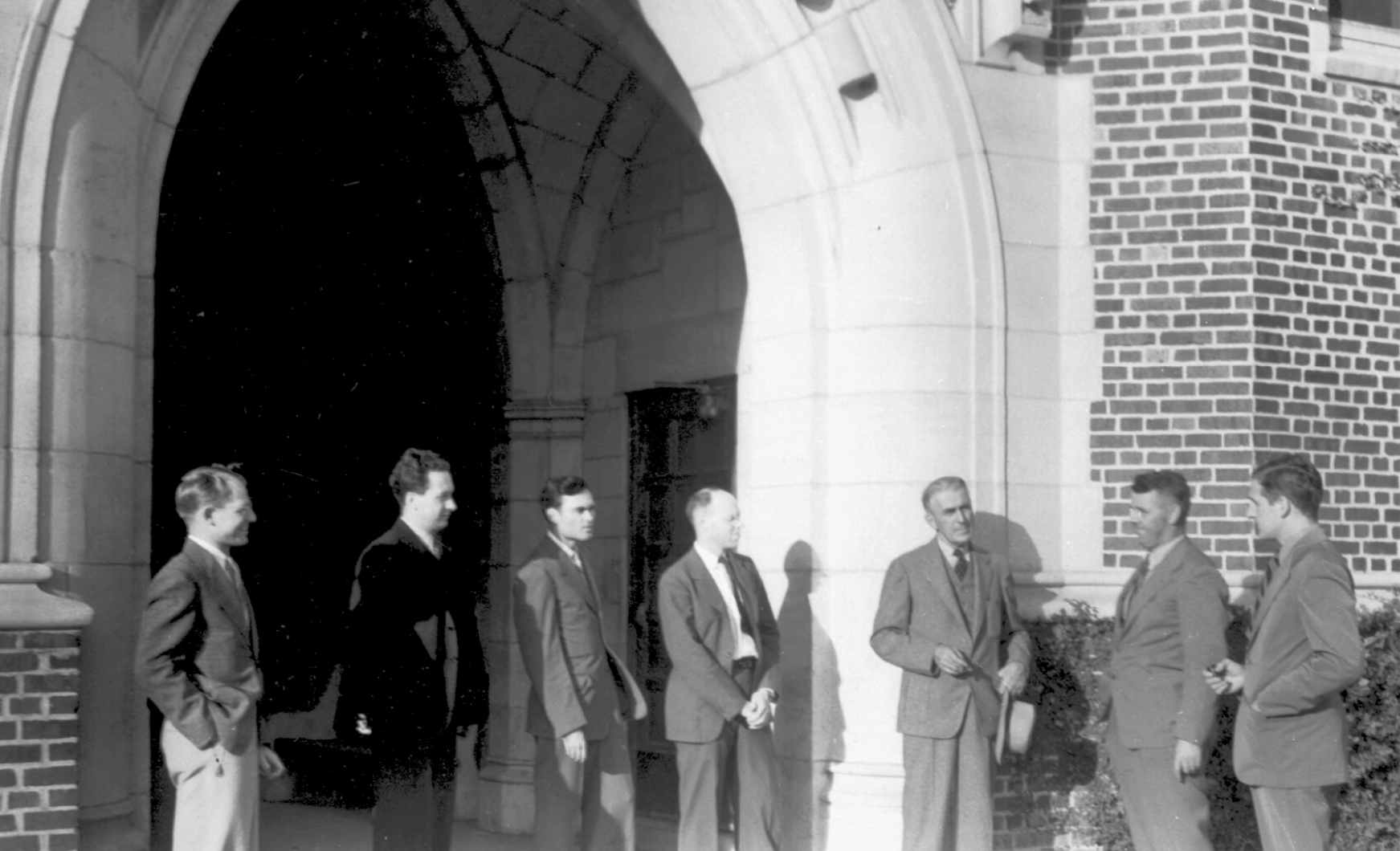 Rudolph Weaver, architect for the Florida Board of Control,and six men stand near the entry arch at Sledd Hall