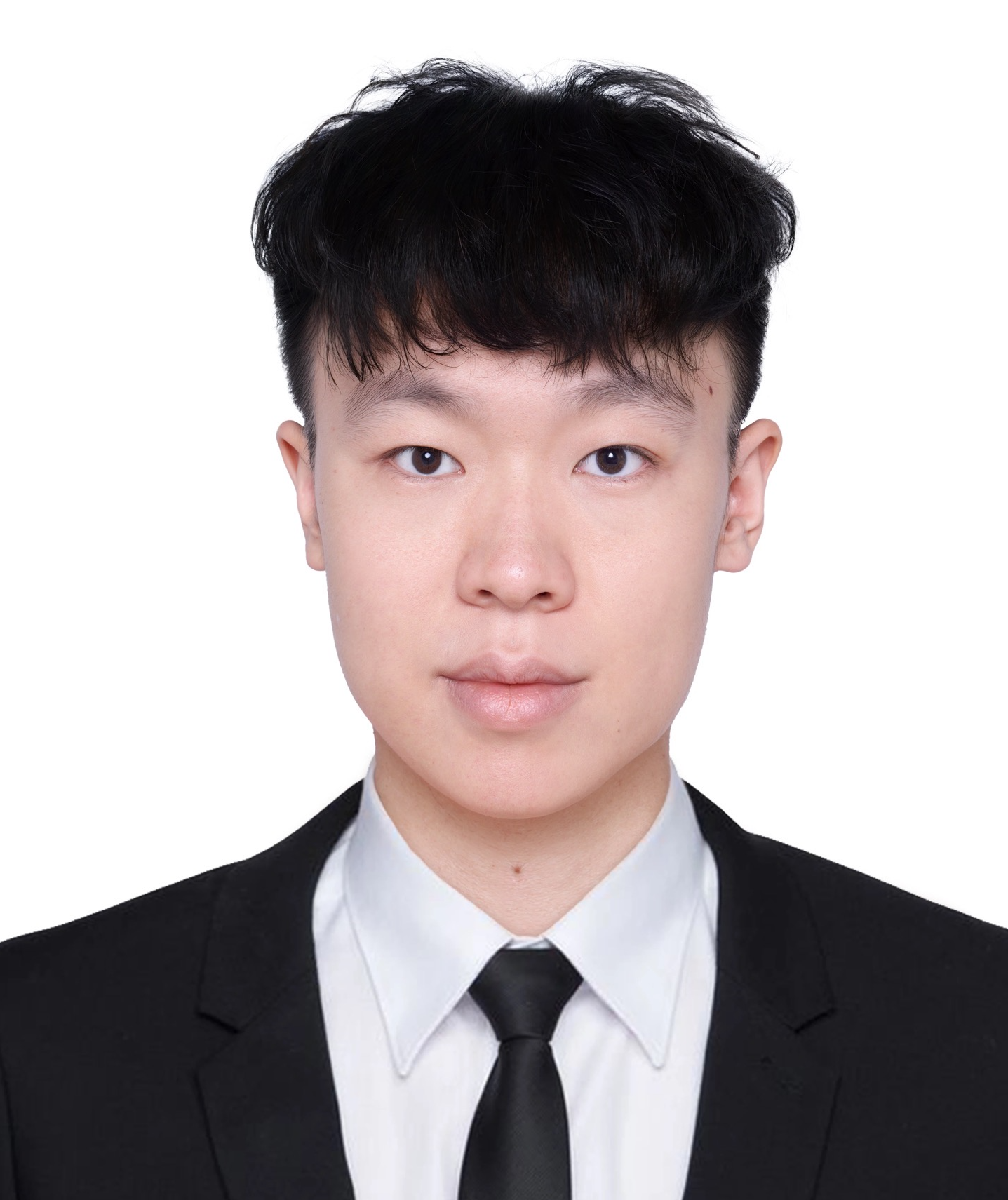 A young man with short black hair wearing a black suit, white shirt, and black tie poses for a formal portrait against a plain white background.