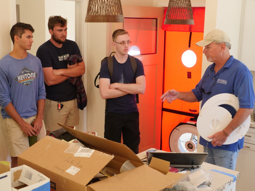 SBE students standing in a kitchen learning about blower door testing.