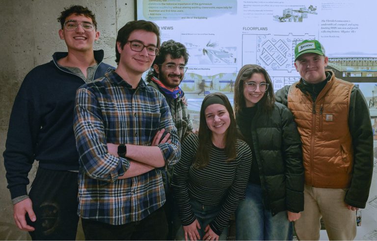 Six young adults stand and smile in front of a wall displaying architectural posters and floorplans. The group appears relaxed and happy, with some wearing glasses, sweaters, and jackets. Their names are Roiler Acosta, Aelly Alwardi, Logan Chappell, Gabriella Childers, Sofia Lopez and Isidoro Vilarino.