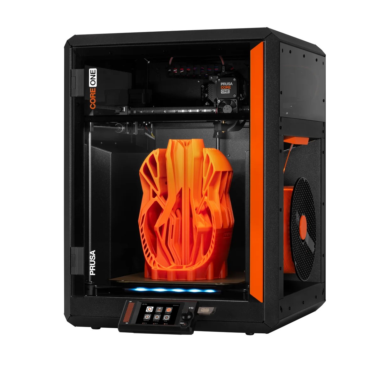 A black and orange 3D printer with a touchscreen display is printing a large, intricate orange object resembling an abstract sculpture inside its enclosed chamber.